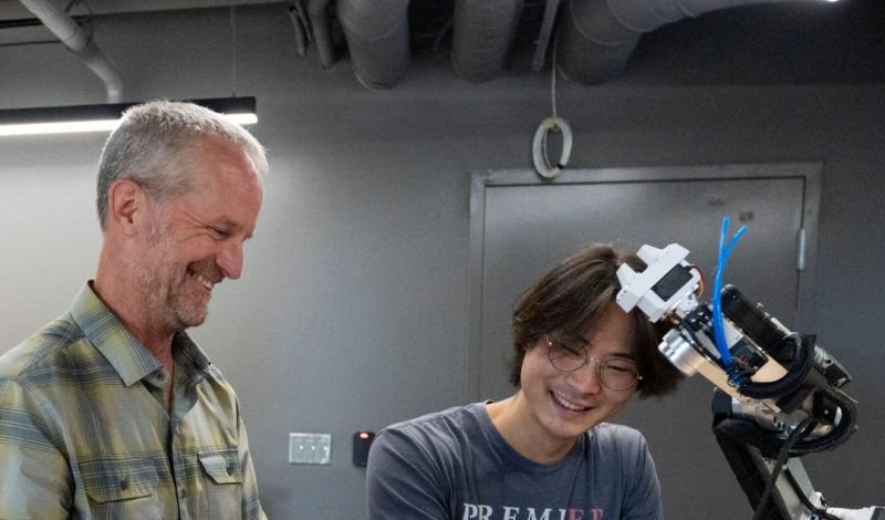 A Denison professor and student smile as they work on a robotics project