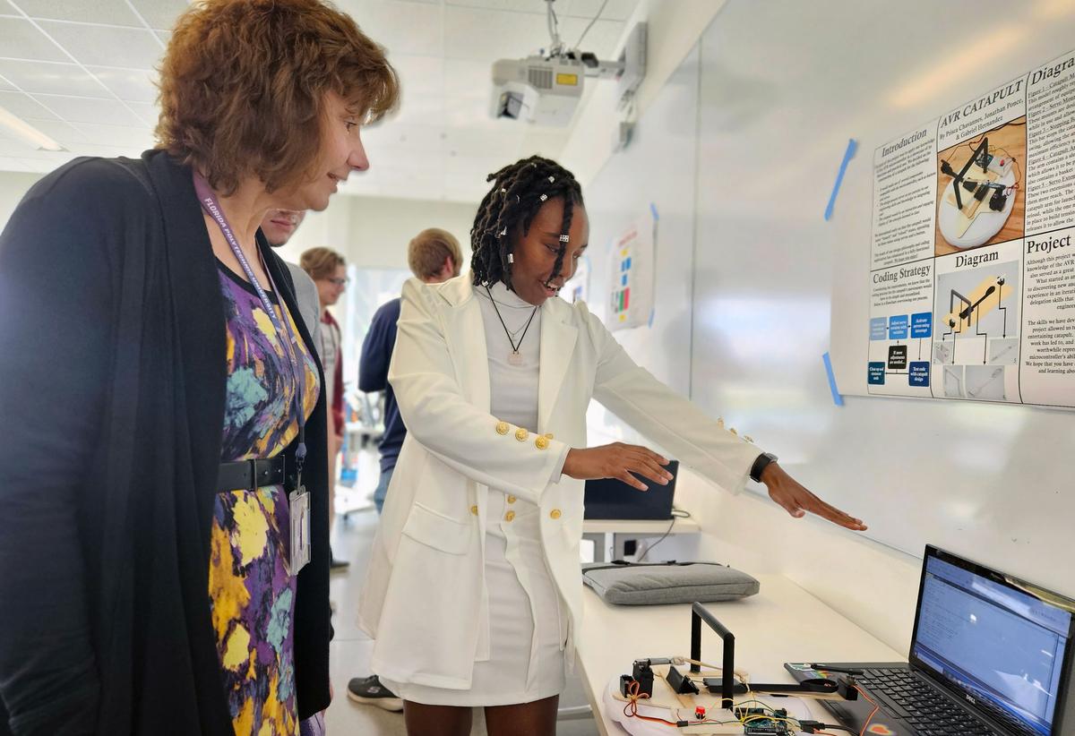 A Florida Poly student presents a microcontroller project poster to a faculty member